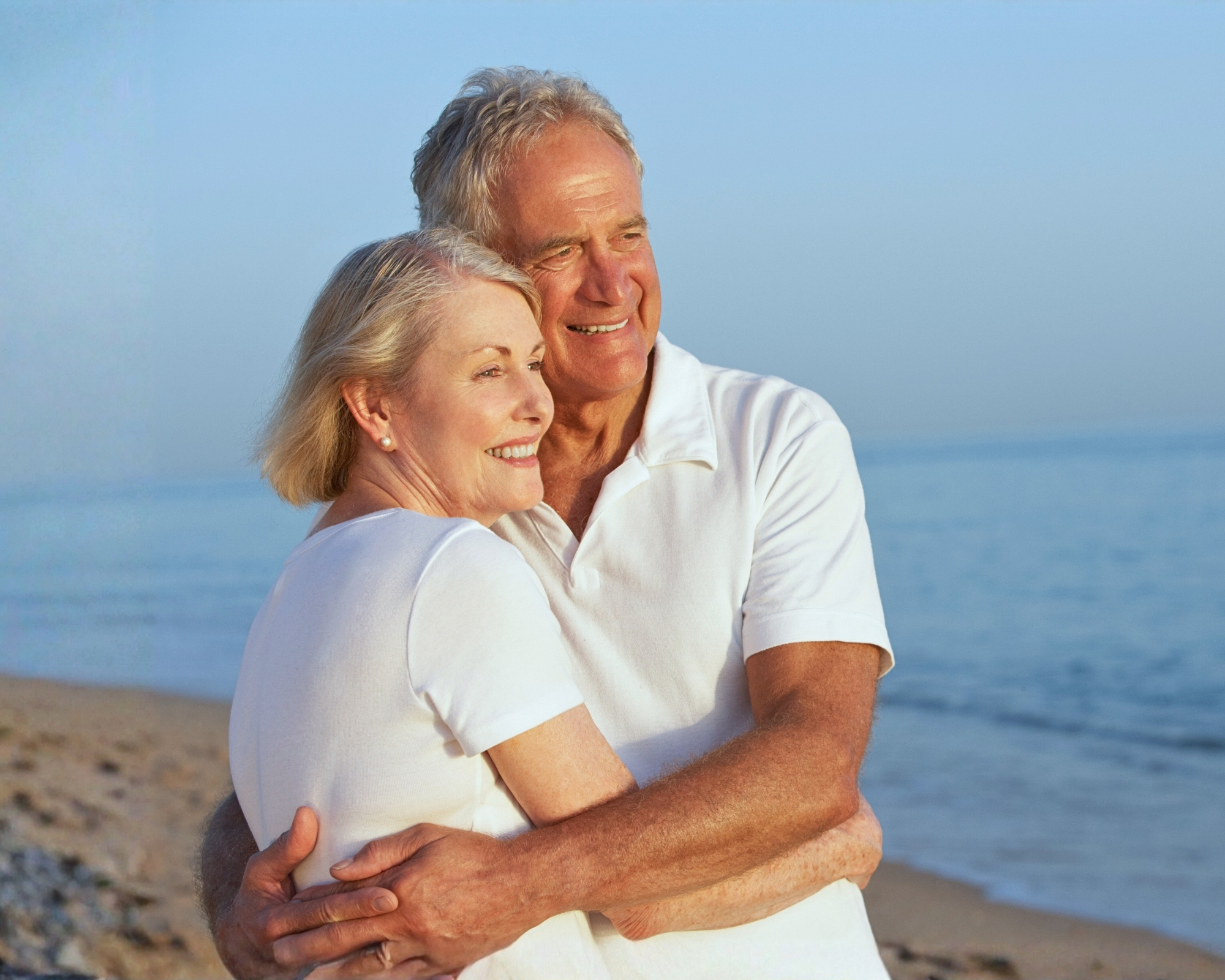 Retired Caucasian couple standing together on the Spanish coast, enjoying the seaside setting.