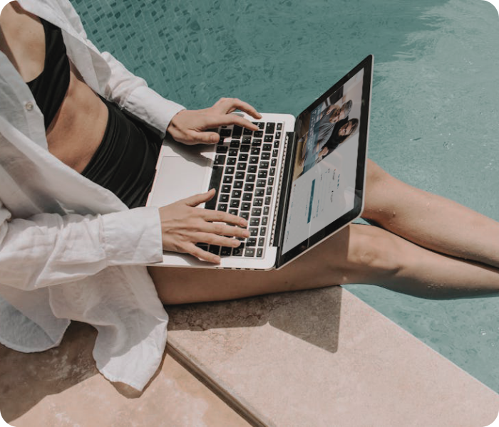 Woman sitting by a private pool using her laptop to complete tax registration on the IberianTax website